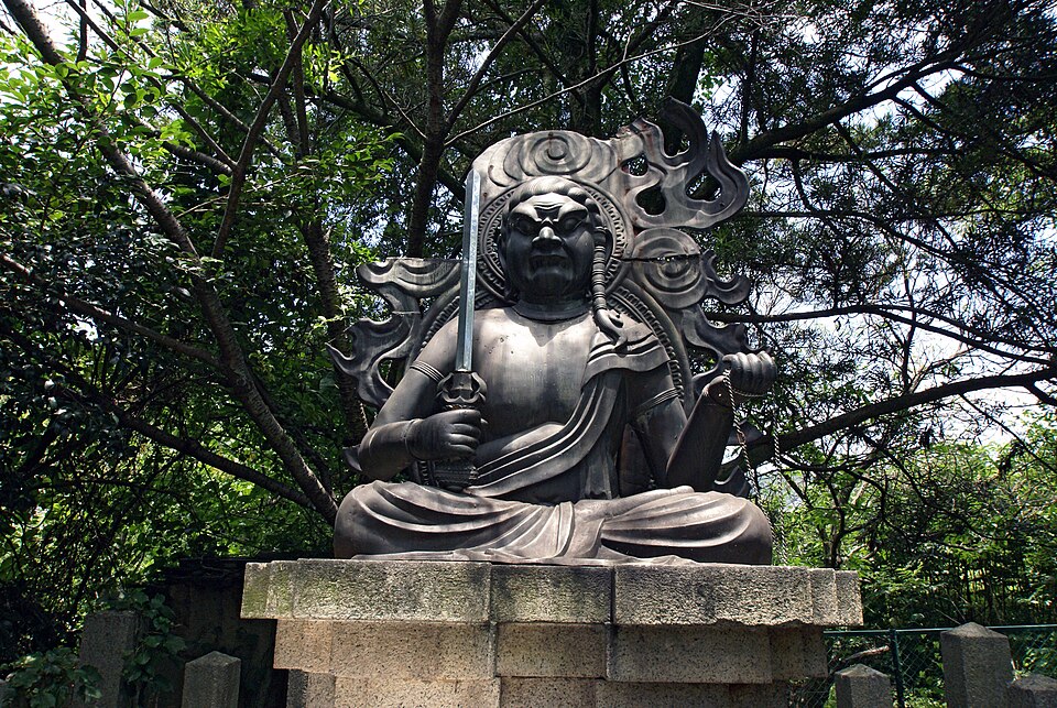 根来寺の木々の下にある屋外の不動像